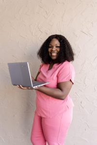 Medical professional in pink scrubs holding a laptop